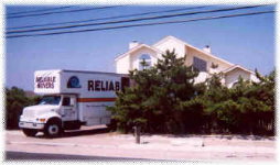 Movers from Classic Moving & Storage carrying a quilt-padded sofa during a residential move