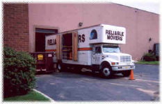 Commercial movers loading a Classic Moving & Storage truck at a building loading dock